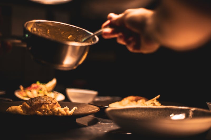Professional chef plating food with foam in restaurant kitchen